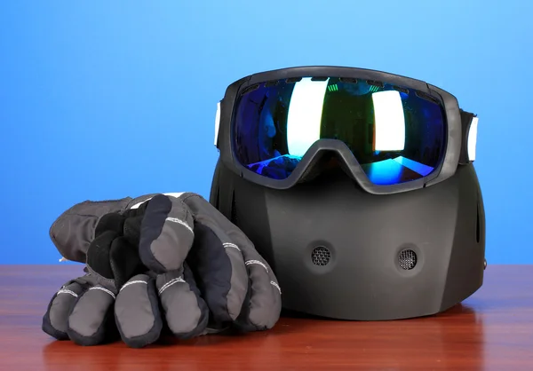 Winter sport glasses, helmet and gloves, on blue background — Stock Photo, Image