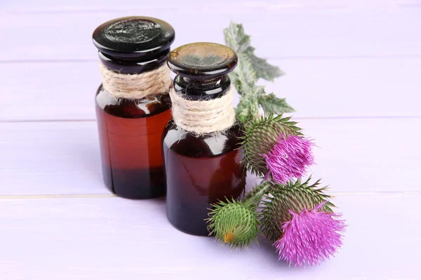 Garrafas de medicina com flores de cardo em fundo de madeira — Fotografia de Stock