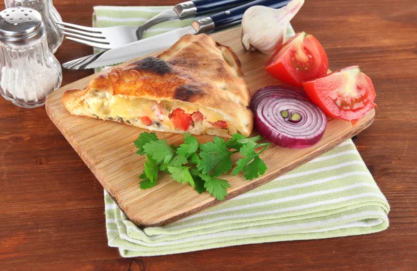 Pizza calzone op houten bord op servet op houten tafel — Stockfoto