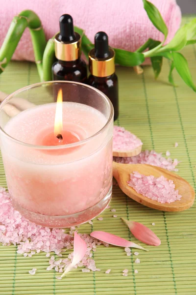 Hermoso entorno de spa con vela rosa en la estera de bambú —  Fotos de Stock