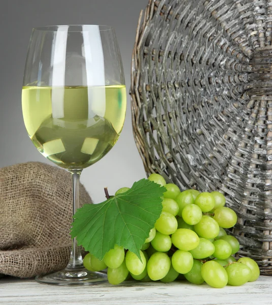 Reife köstliche Trauben mit einem Glas Wein auf dem Tisch vor grauem Hintergrund — Stockfoto