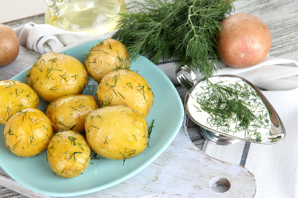 Boiled potatoes on platen on wooden board near napkin on wooden table