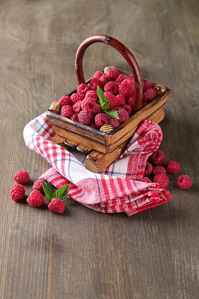 Спелые сладкие малины в корзине на деревянном фоне — стоковое фото