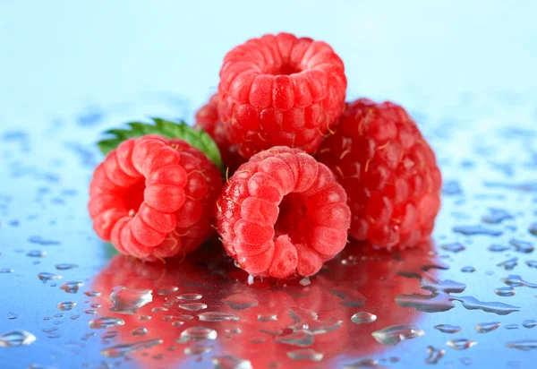 Rijpe zoete frambozen met druppels, op blauwe achtergrond — Stockfoto