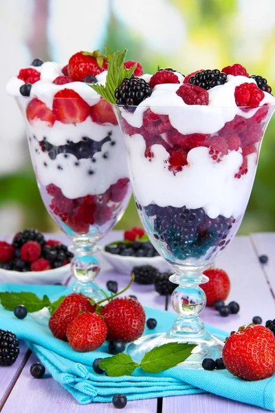 Natural yogurt with fresh berries on wooden table on green background — Stock Photo, Image