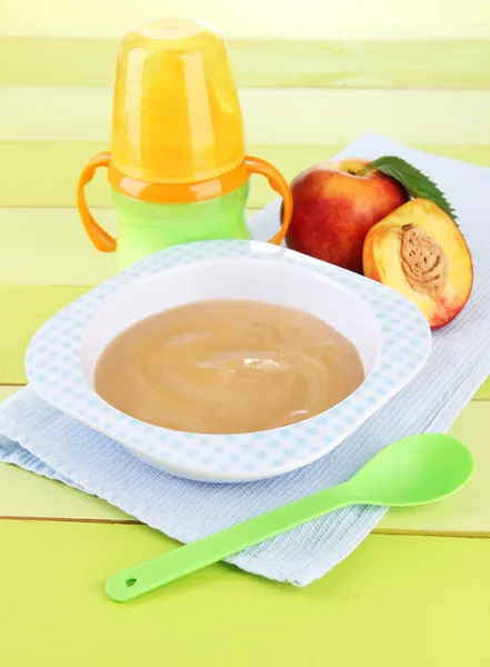 Leckeres Babyfruchtpüree und Babyflasche auf Holztisch — Stockfoto