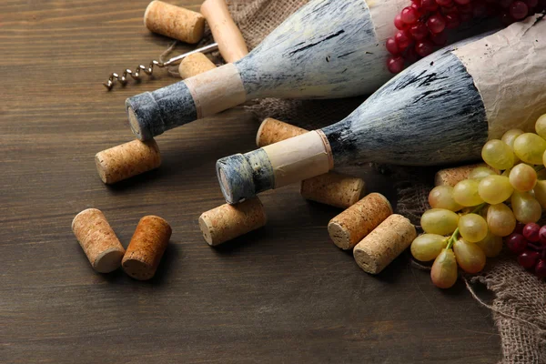 Old bottles of wine, grapes and corks on wooden background — Stock Photo, Image