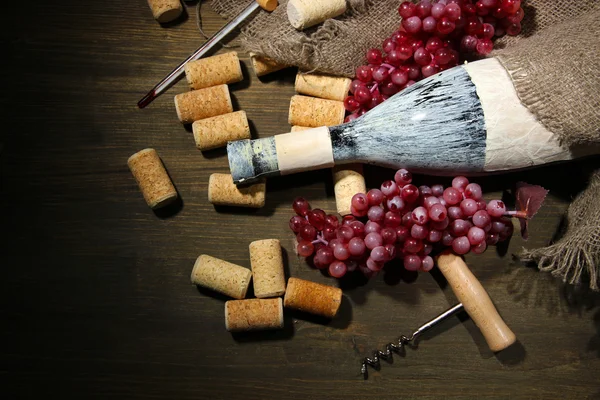 Old bottle of wine, grapes and corks on wooden background — Stock Photo, Image
