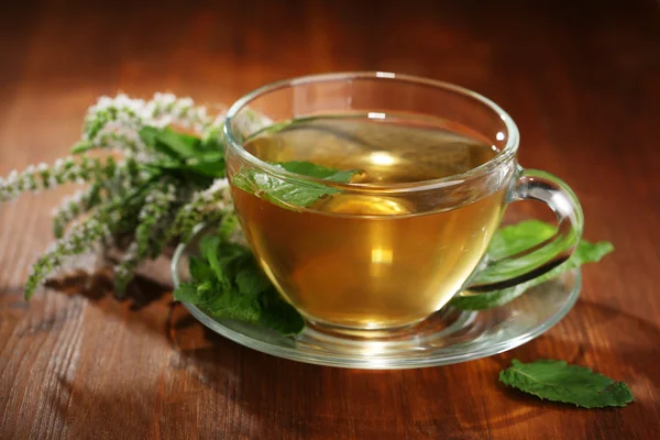 Cup of herbal tea with fresh mint flowers on wooden table — Stock Photo, Image