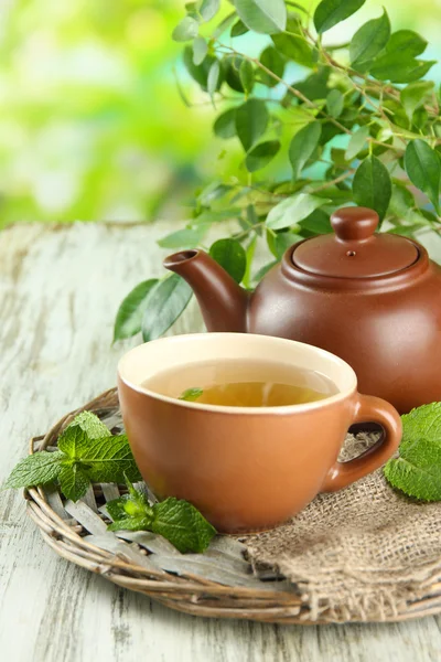 Theepot en kopje kruiden thee met verse munt op houten tafel — Stockfoto