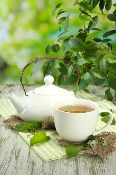 Teekanne und Tasse Kräutertee mit frischer Minze auf Holztisch — Stockfoto