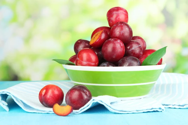 Mogna plommon i skål på träbord på naturliga bakgrund — Stockfoto