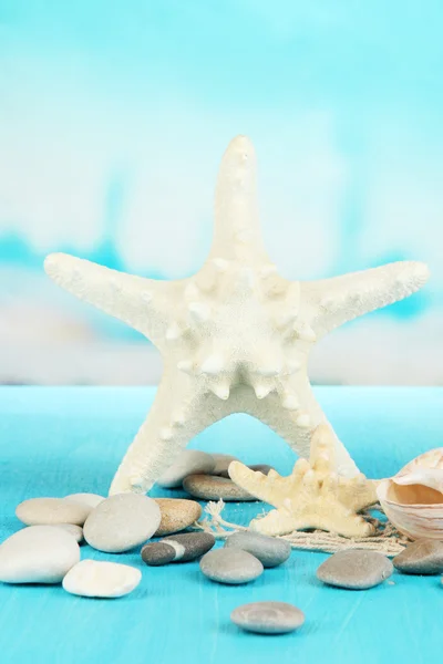 White starfishes on blue wooden table on sea background — Stock Photo, Image