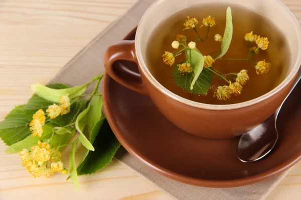 Cup of tea with linden on napkin wooden table — Stock Photo, Image