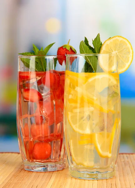 Glasses of fruit drinks with ice cubes on table in cafe — Stock Photo, Image