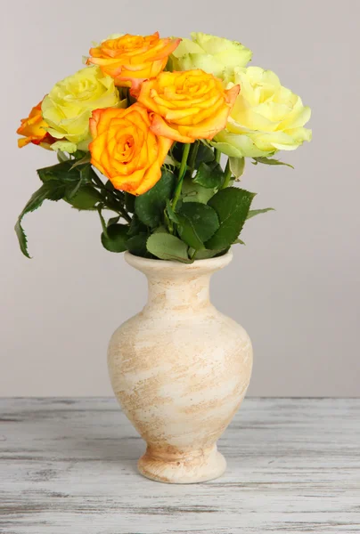 Mooi boeket rozen in vaas op tafel op grijze achtergrond — Stockfoto