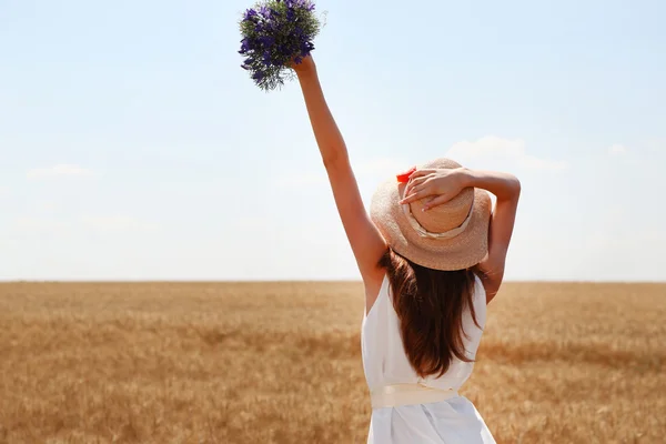 Portret van mooie jonge vrouw met bloemen op het gebied — Stockfoto