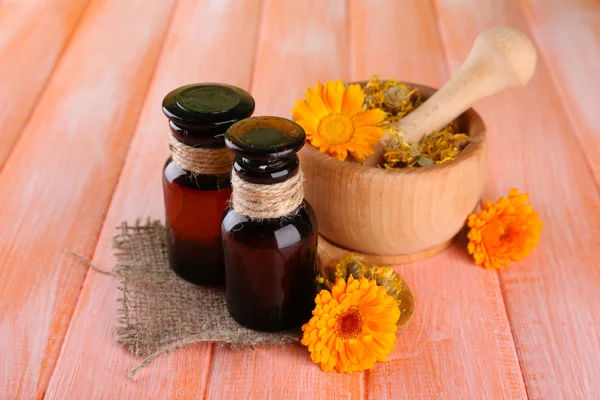 Medicine bottles and calendula flowers on wooden background — Stock Photo, Image