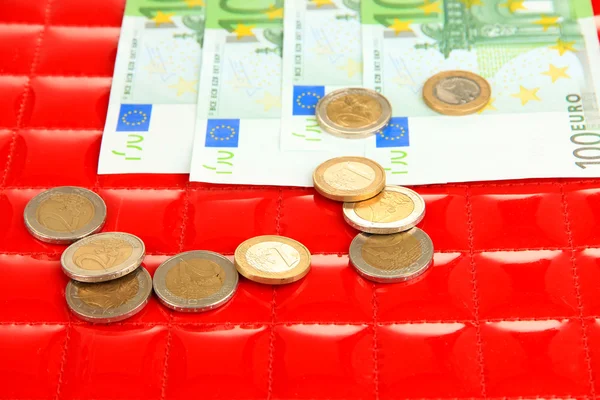 Euro banknotes and euro cents on red background — Stock Photo, Image