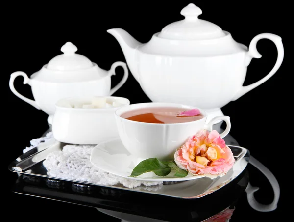 Kettle and cup of tea from tea rose on metallic tray on napkin black background — Stock Photo, Image