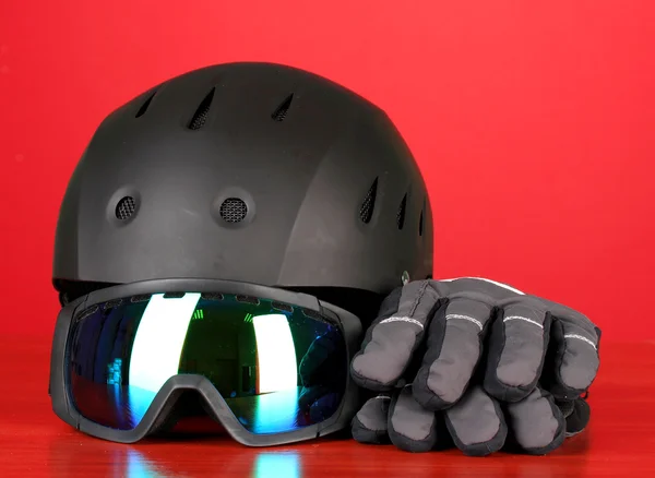 Occhiali sportivi invernali, casco e guanti, su sfondo rosso — Foto Stock
