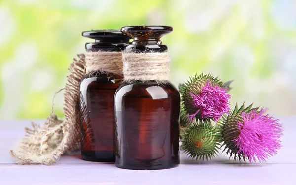 Medizinflaschen mit Distelblumen auf Naturhintergrund — Stockfoto