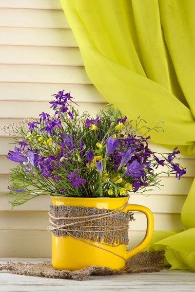 Beautiful bouquet of wildflowers in cup on wooden table — Stock Photo, Image