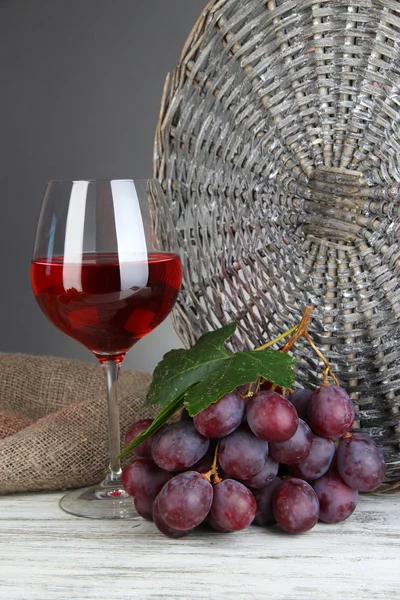 Rijp heerlijke druiven met glas wijn op tafel op grijze achtergrond — Stockfoto