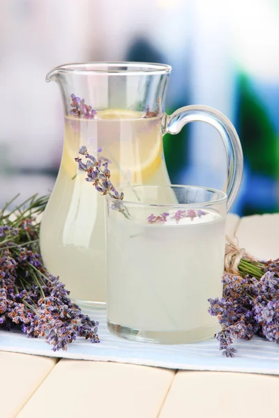 Lavender lemonade in glass jug, on napkin, on bright background — Stock Photo, Image