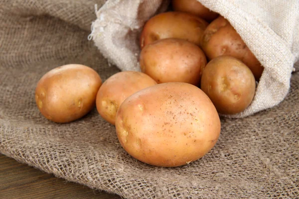 Potato in sack on sackcloth, on wooden table — Stock Photo, Image