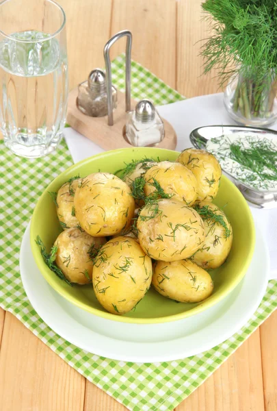 Pommes de terre bouillies sur les plateaux sur les serviettes sur la table en bois — Photo