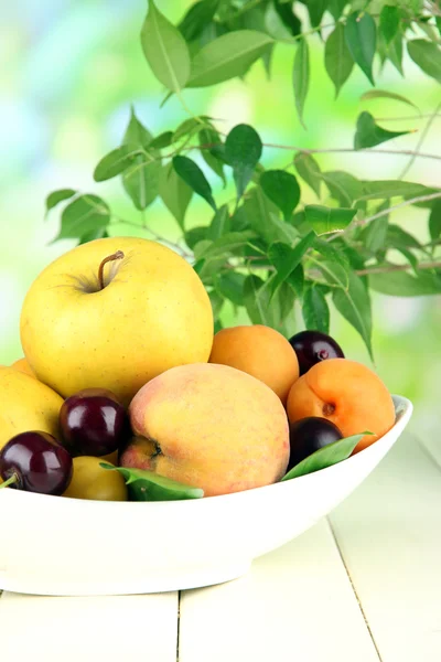 Helle Sommerfrüchte im Teller auf Holztisch auf natürlichem Hintergrund — Stockfoto