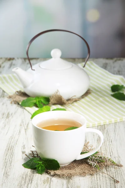 Tetera y taza de té de hierbas con flores de menta fresca en la mesa de madera —  Fotos de Stock