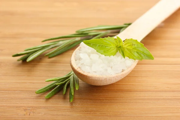 Sal en cuchara con romero fresco y albahaca sobre fondo de madera — Foto de Stock