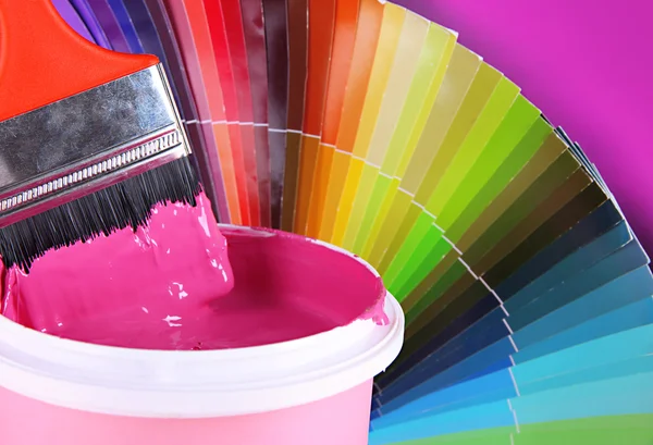 Paint pot, paintbrush and coloured swatches close up — Stock Photo, Image