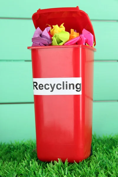 Reciclagem bin com papéis na grama em fundo azul claro — Fotografia de Stock