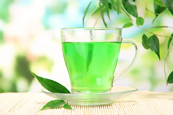 Yeşil çay doğal zemin üzerine bambu hasır üzerinde şeffaf bardak — Stok fotoğraf