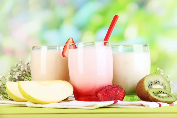 Pyszne jogurty z owocami w okularach na drewnianym stole na naturalne tło — Zdjęcie stockowe