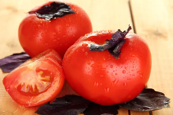 Pomodori freschi e foglie di basilico su fondo di legno — Foto Stock