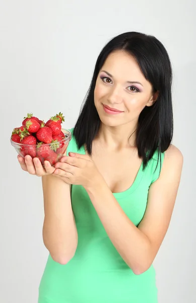 Hermosa joven con fresas sobre fondo gris — Foto de Stock