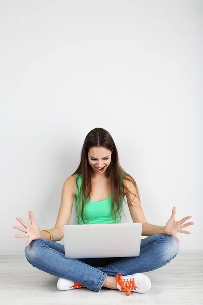 Bella giovane donna seduta con computer portatile in camera — Foto Stock