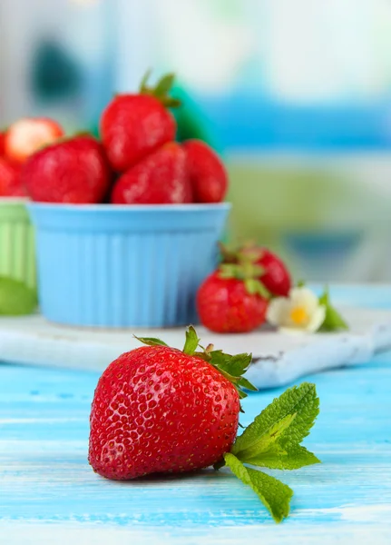 Reife süße Erdbeeren in Schalen auf blauem Holztisch — Stockfoto