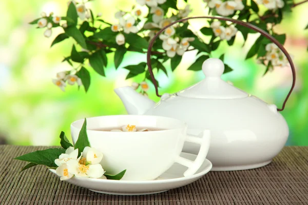 Xícara de chá com jasmim, no tapete de bambu, no fundo brilhante — Fotografia de Stock