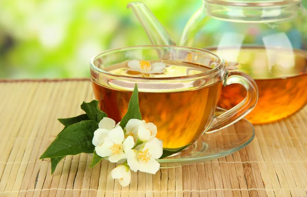 Cup of tea with jasmine, on bamboo mat, on bright background — Stock Photo, Image