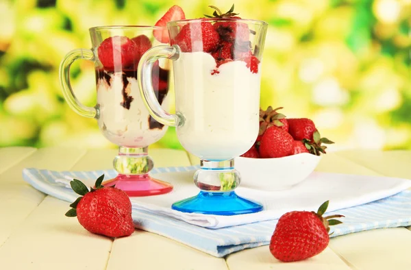 Deliziosi dessert alla fragola in vaso di vetro su tavolo di legno su sfondo naturale — Foto Stock