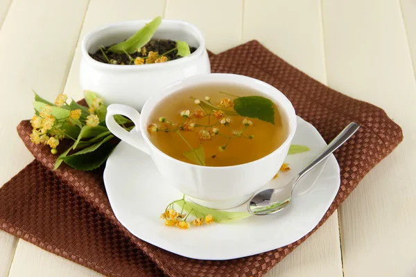 Kopje thee met linden op servet op houten tafel — Stockfoto