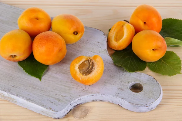 Apricots on board on wooden table — Stock Photo, Image