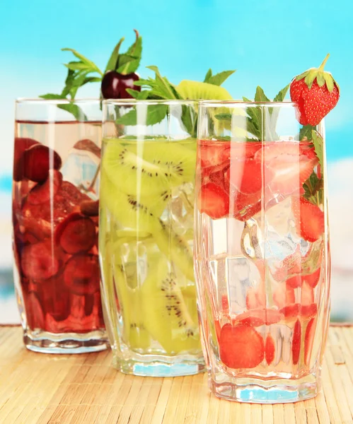 Okulary napojów owocowych z kostkami lodu na niebieskim tle — Zdjęcie stockowe