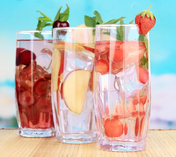 Bicchieri di bevande alla frutta con cubetti di ghiaccio su sfondo blu — Foto Stock