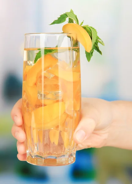 Vaso de bebida de frutas con cubitos de hielo en la mano sobre fondo brillante —  Fotos de Stock